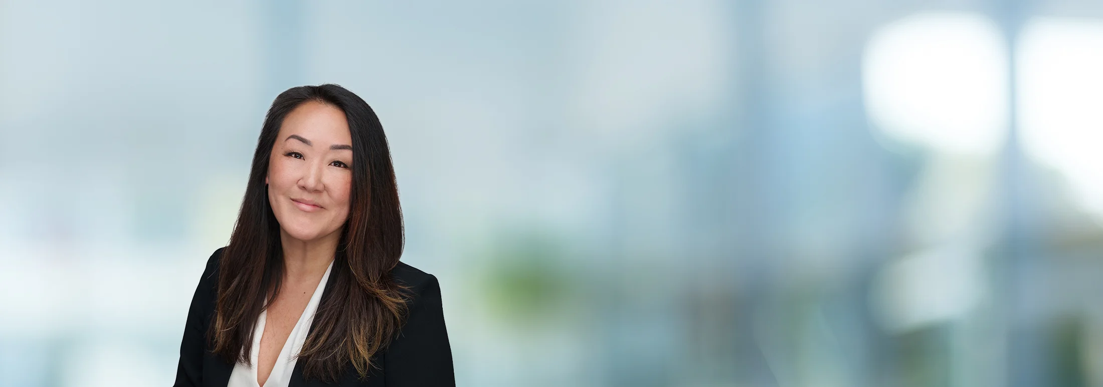 A photo of attorney, Sumy Kim, against a softly blurred office background
