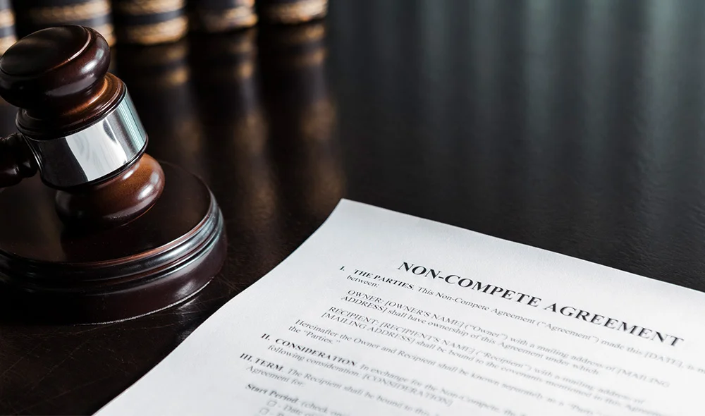 Close-up of a desk displaying several thick legal books stacked upright on the left side, with dark covers and gold-lettered spines. In the foreground, a printed document lies flat on the desk.